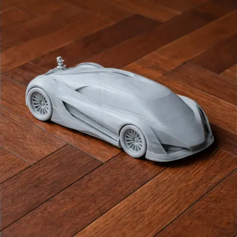 Gray 3D-printed model of a sleek, futuristic car on a wooden floor.