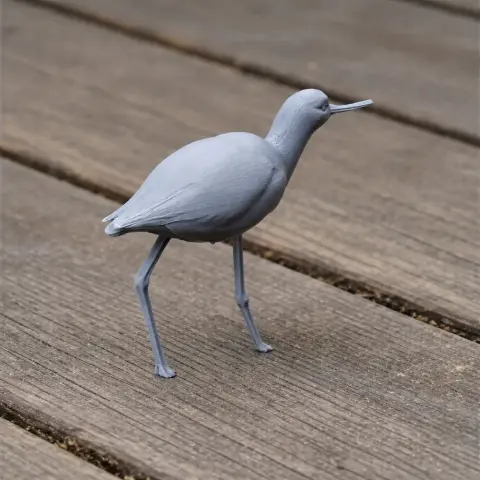 A gray 3D-printed model of a bird with long legs and a slender beak on a wooden surface.