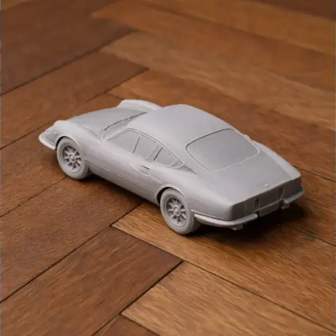 3D-printed model of a classic sports car on a wooden surface.
