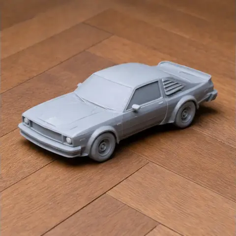Gray 3D-printed model of a Dodge Aspen car on a wooden surface.