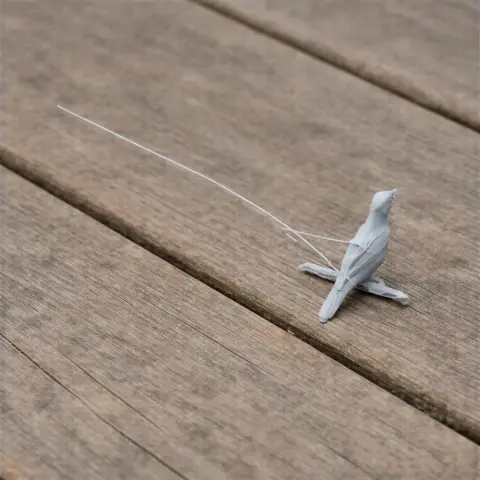 A small 3D printed model of a bird with a long tail, placed on a wooden surface.