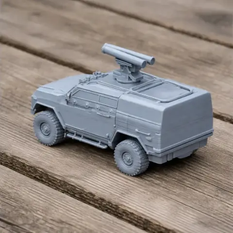3D-printed model of a light armored vehicle with turret, on a wooden surface.