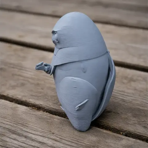 3D-printed model of a stylized, simplified owl with prominent wings and small feet on a wooden surface.