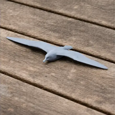 A 3D-printed model of a Bannerman's shearwater, depicted in a gliding position on a wooden surface.
