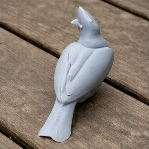 Gray 3D-printed bird model, perched, with detailed feathers, on a wooden surface.