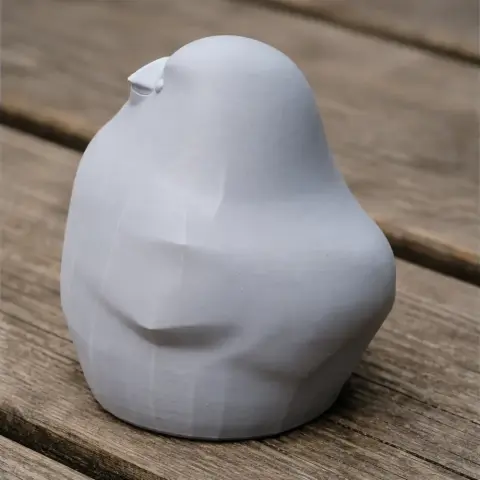 Smooth, abstract 3D model of a bird, resembling a bannerman's weaver, set on a wooden surface.