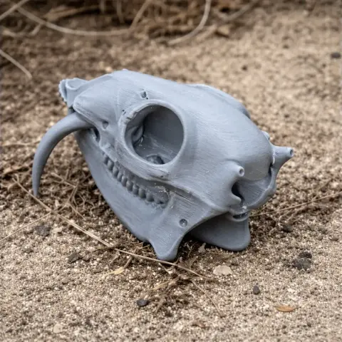 3D-printed grey water deer skull replica resting on sandy ground.