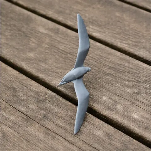 A 3D-printed model of a Barau's petrel bird with outstretched wings on a wooden surface.