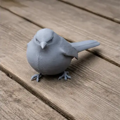 Gray 3D-printed model of a Barbuda warbler bird on a wooden surface.