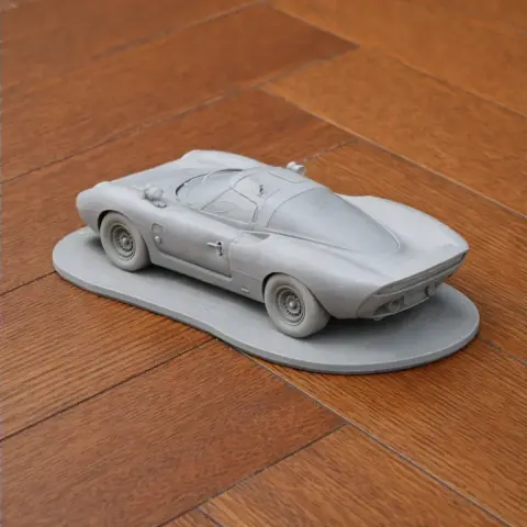 Scale model car of Ecurie Ecosse LM69 on a wooden surface, designed for 3D printing.