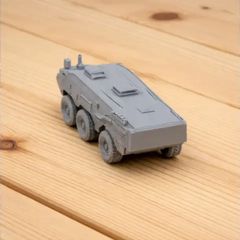 3D printed gray military vehicle model with six wheels on a wooden surface.