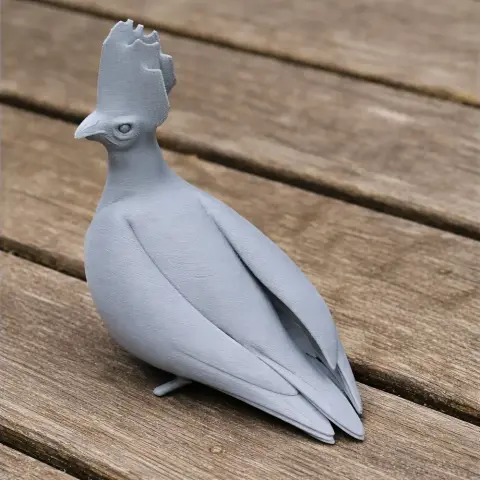3D printed model of a bare-faced go-away-bird with a crest, sitting on a wooden surface.