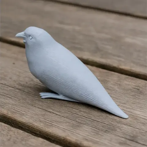 A 3D printed model of a bare-headed laughingthrush bird, shown in a pale color, on a wooden surface.