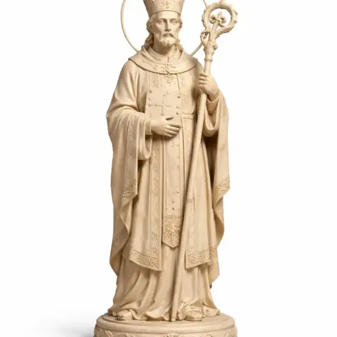 A detailed statue of a saint in robes holding a staff, with a halo behind the head.