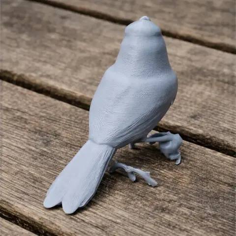 3D-printed model of a bird with intricate feather details, perched on a textured surface.