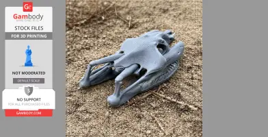 A detailed 3D-printed yellow anaconda skull replica lying on sandy ground.