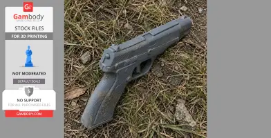 A 3D-printed gray handgun prop lying on grass and soil, showcasing detailed textures.