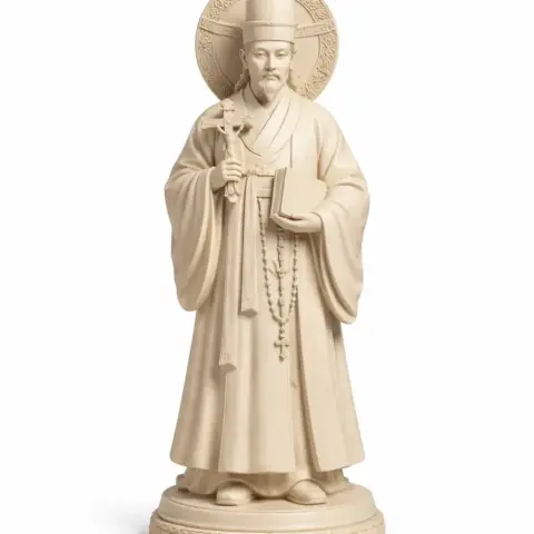 A detailed statue of a robed figure with a halo, holding a book and a cross.