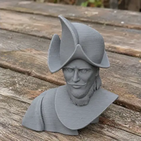 3D-printed bust of a historical figure with a folded hat and beard, on a wooden table.