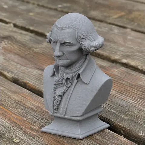 3D-printed bust of a historical figure with detailed clothing, set on a wooden surface.