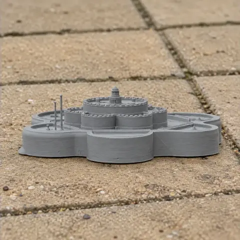 A 3D-printed model of a historic castle with round bastions on a stone-tiled surface.