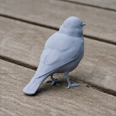 Gray 3D printed bird model with detailed features on a wooden surface.