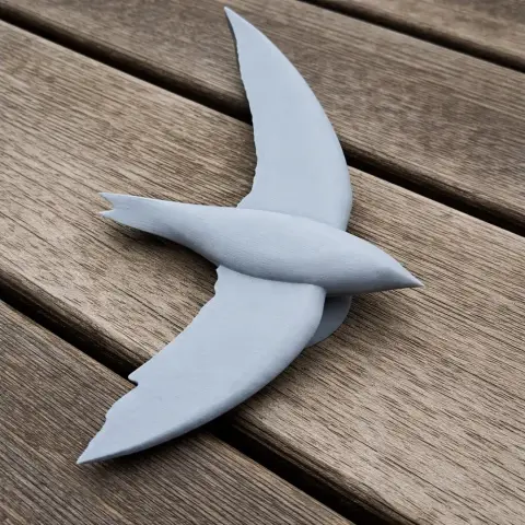 A 3D printed prehistoric bird model with long wings, placed on a wooden surface.