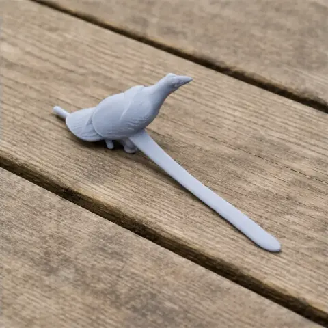 A 3D-printed model of a prehistoric bird with a long tail on a wooden surface.