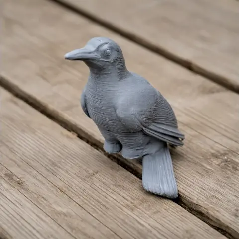 Gray 3D printed model of a prehistoric bird, sitting on a wooden surface.