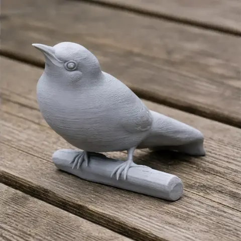 3D printed model of a bird perched on a small branch, set on a wooden surface.
