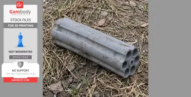 A 3D-printed gray revolver cylinder prop on grass and soil, part of a cosplay accessory.