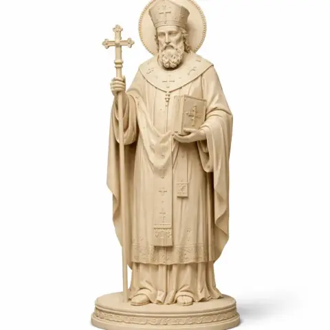 A detailed 3D statue of a bearded man in religious attire, holding a cross and a book.