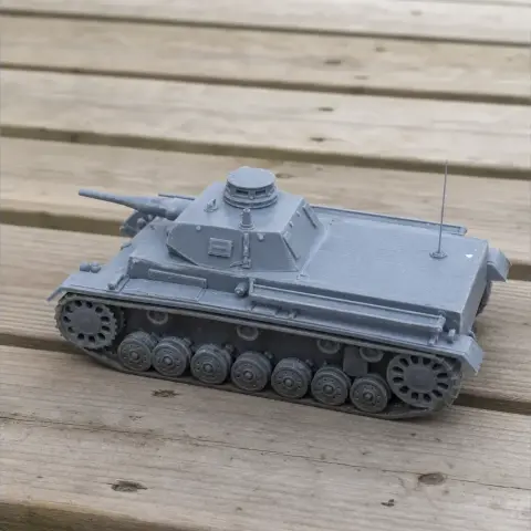 Gray Panzer III tank model with turret and tracks, displayed on a wooden surface.