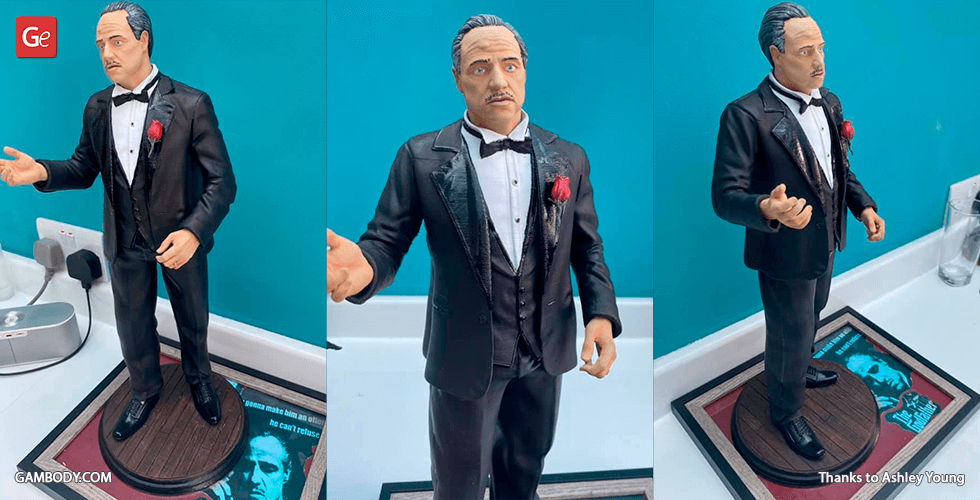 3D printed figure of a man in a black tuxedo with a red rose, posed with raised hands.