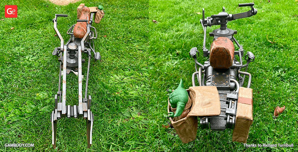 A detailed 3D-printed Mandalorian speeder bike model with a green creature and bags on green grass.