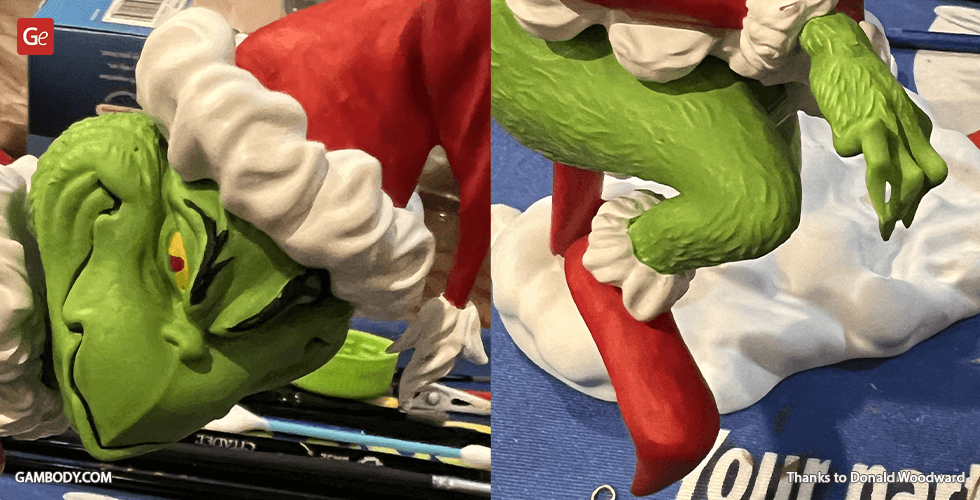 A 3D model of a green, grumpy creature in a red Santa suit on snow, likely representing the Grinch.