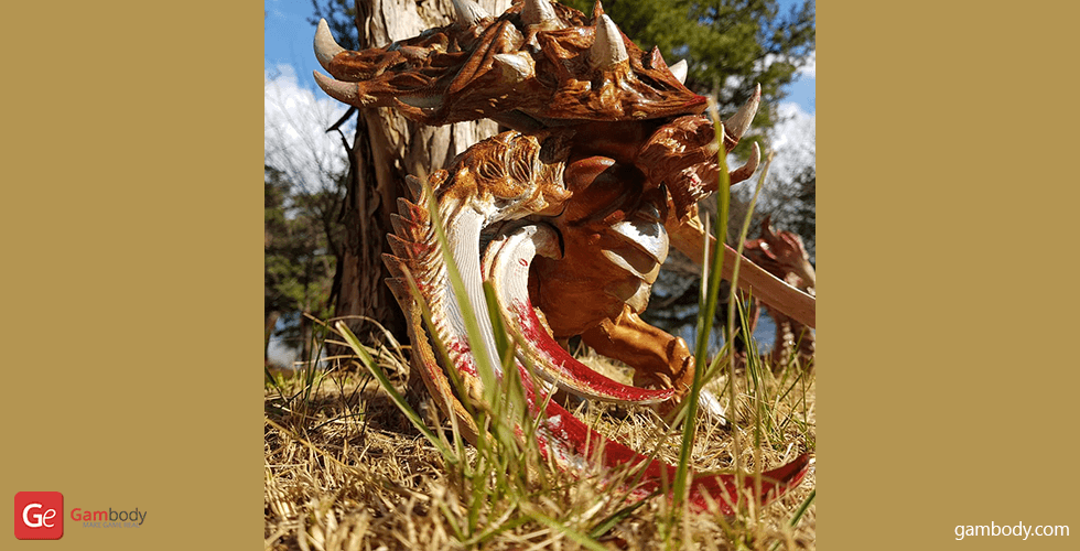 A detailed 3D-printed Ultralisk model from StarCraft, posed outdoors among grass and trees.