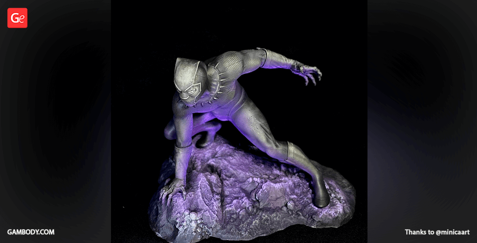 A detailed 3D-printed figure of a superhero crouching on a rocky base, illuminated by purple light.