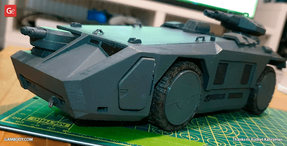 A detailed 3D printed model of a futuristic armored personnel carrier (APC) on a cutting mat.